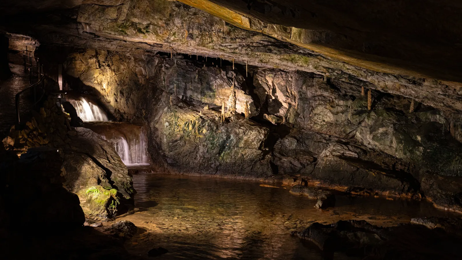 Weite Halle der St. Beatus-Höhlen mit Bachlauf und beleuchteter Felswand
