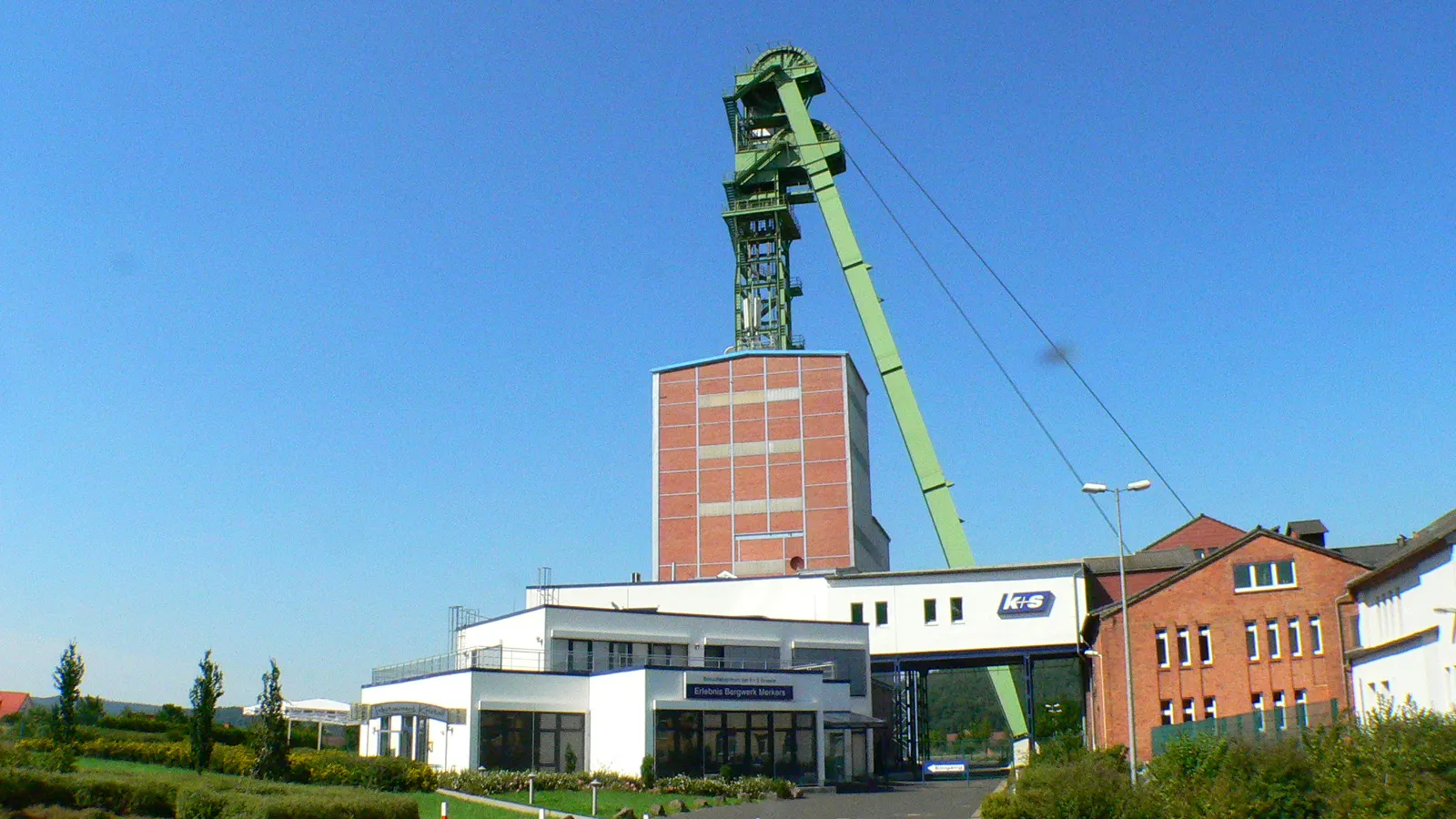 Grünes Fördergerüst über dem Schacht des Erlebnisbergwerks Merkers, davor das Besucherzentrum