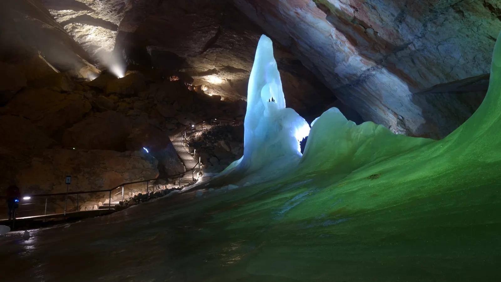 Eisfigur im Parzivaldom der Dachstein-Rieseneishöhle, dahinter der beleuchtete Besucherweg