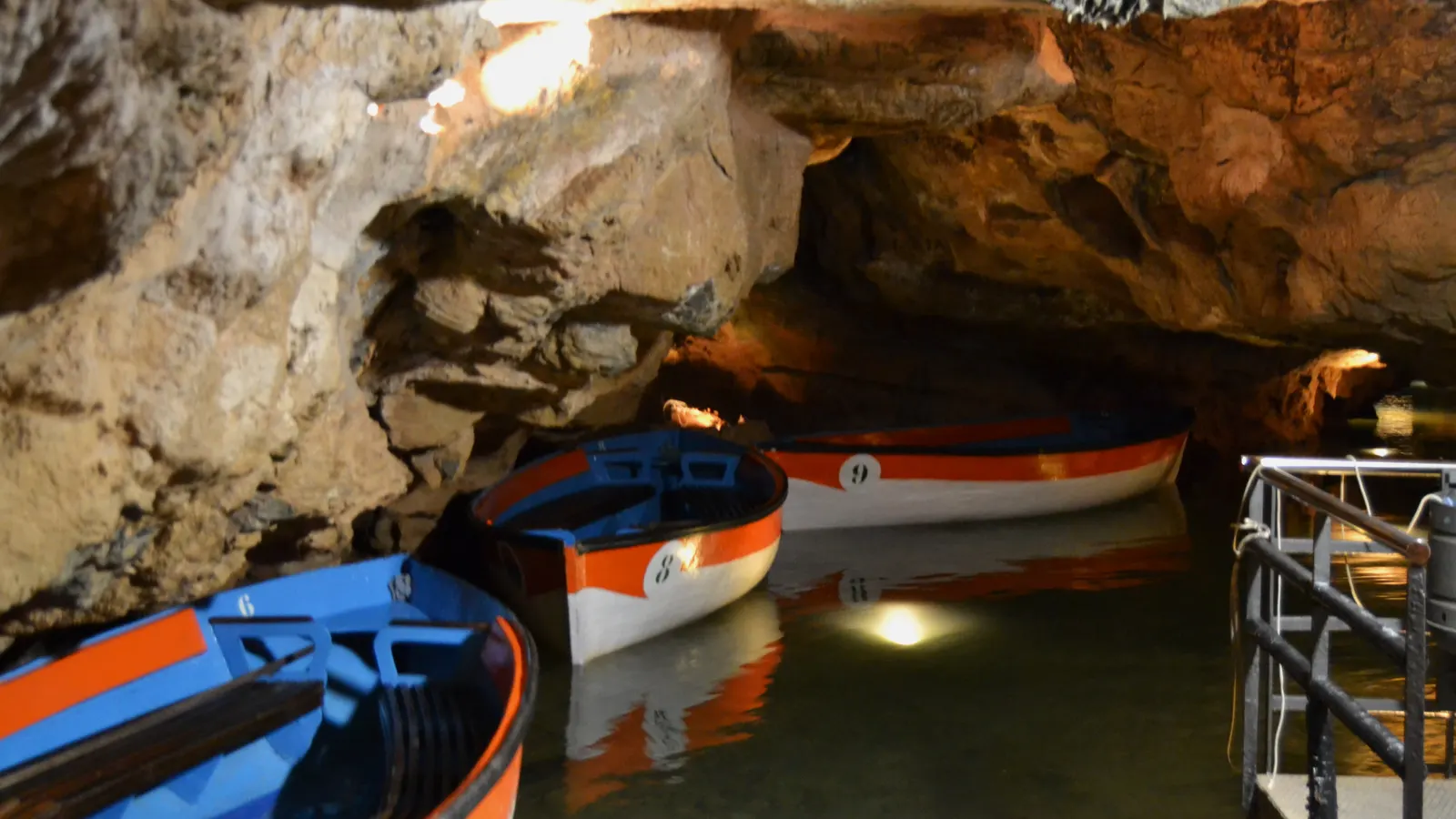 Boote am Anleger im Inneren der Höhlen von San José, beleuchtete Felswände über dem Wasser