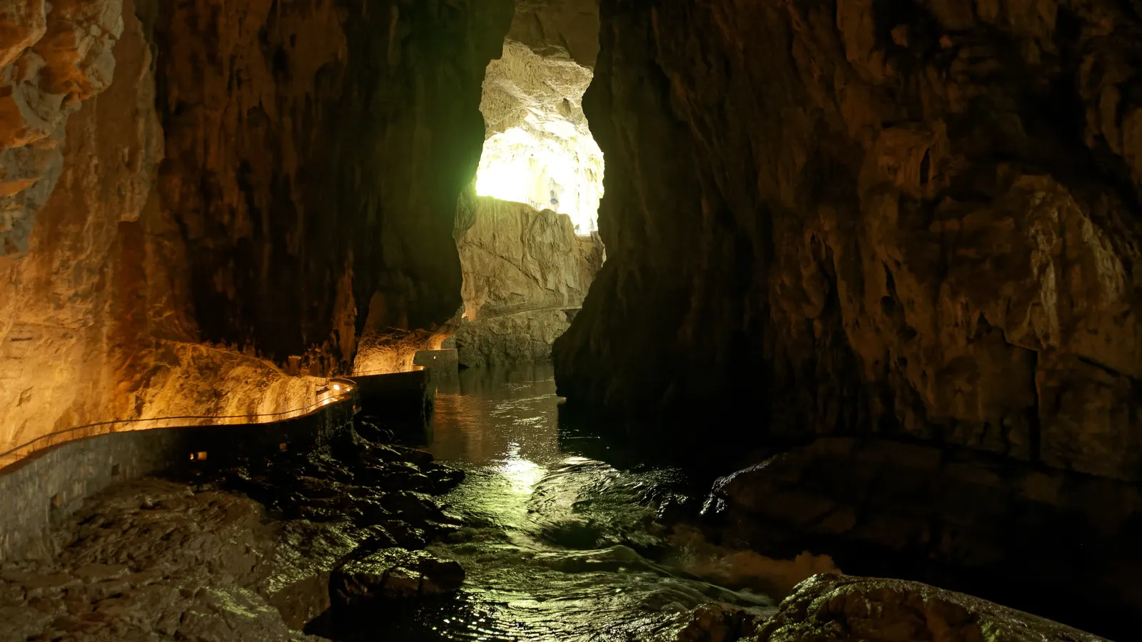 Tageslicht fällt durch eine Felsöffnung auf den Weg an der Reka in den Höhlen von Škocjan