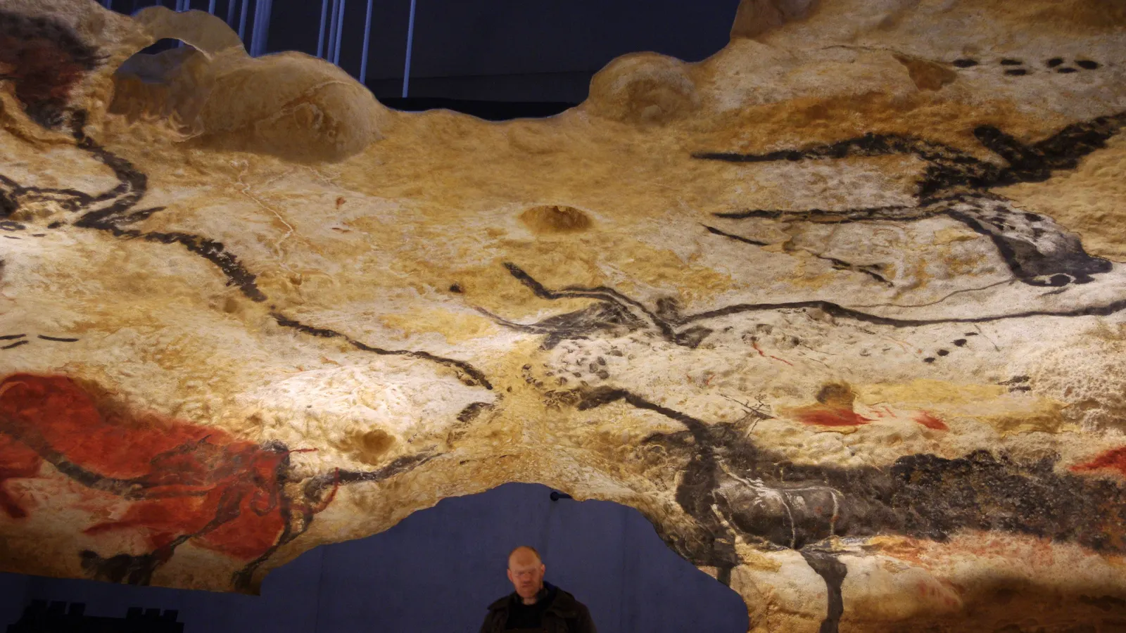 Nachbildung der Stierhalle in Lascaux IV bei Montignac, darunter ein Besucher – die Originalhöhle ist seit 1963 geschlossen