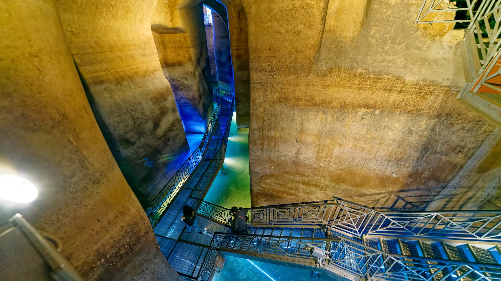 Blau ausgeleuchtete Zisterne Palombaro Lungo unter Matera mit Stahlsteg über dem Wasser