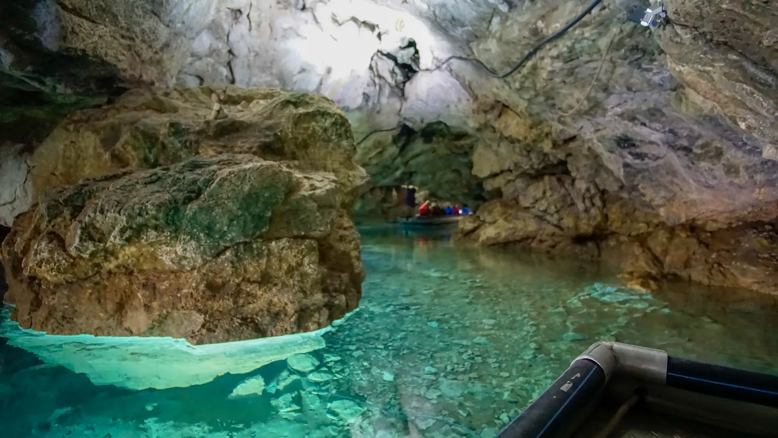 Türkisfarbenes Wasser am Eingang der Wimsener Höhle, ein Boot liegt am Steg